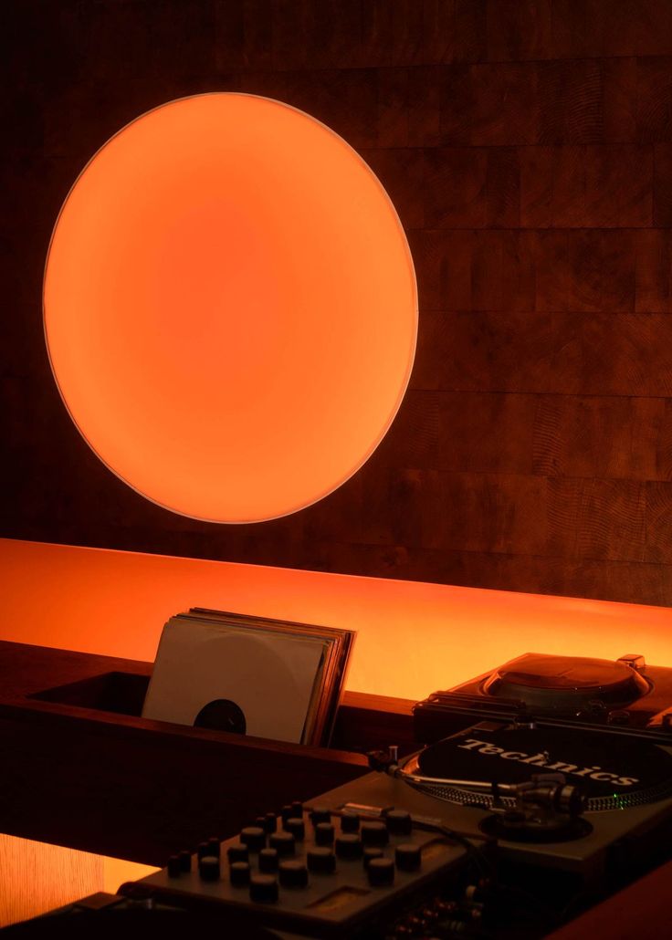 Glowing orange disc light above a Technics turntable setup
